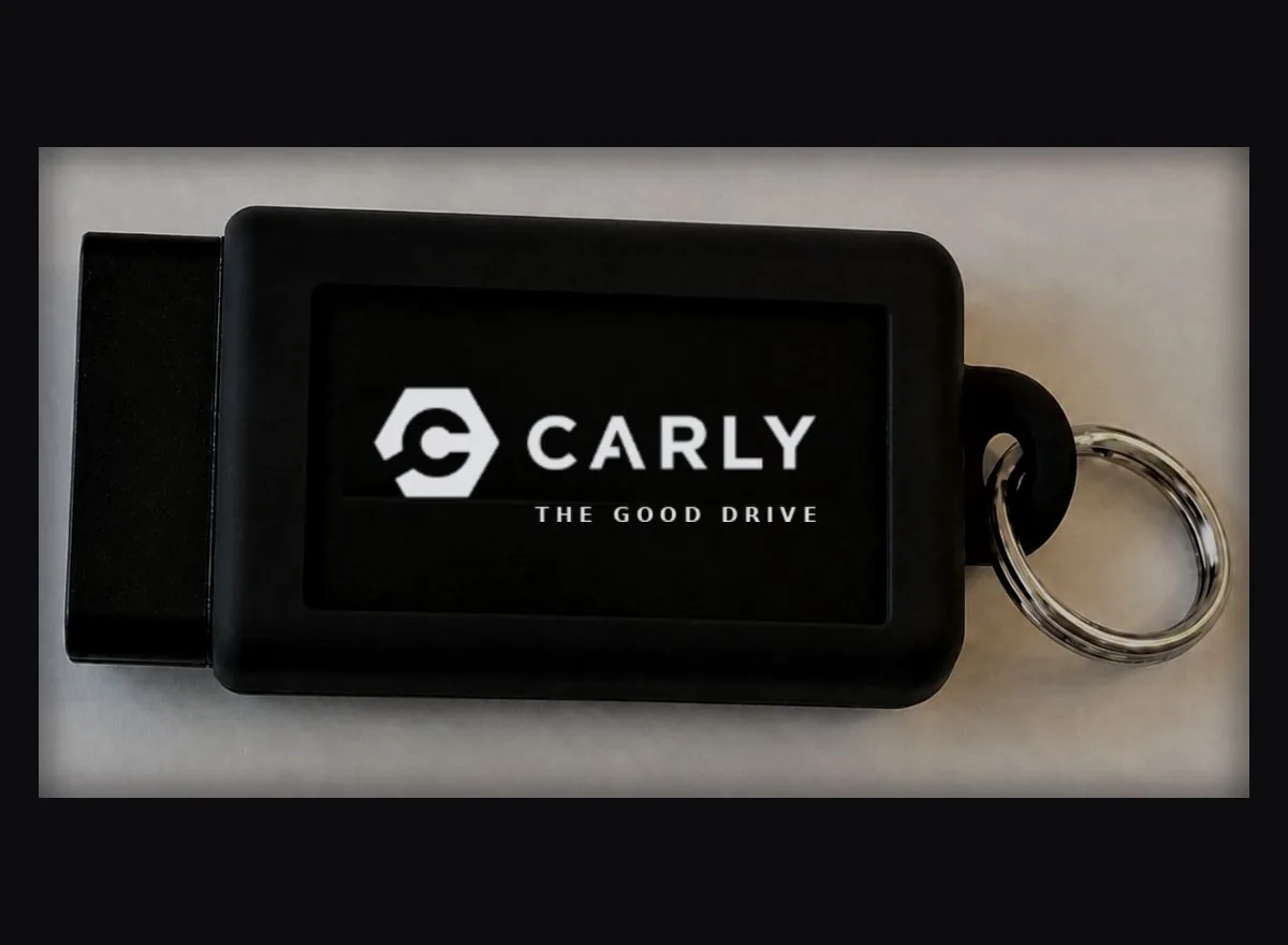 Carly-Schutz-Sleeve — Silikonhülle mit weißem Carly-Schriftzug „THE GOOD DRIVE“ und Metall-Schlüsselring